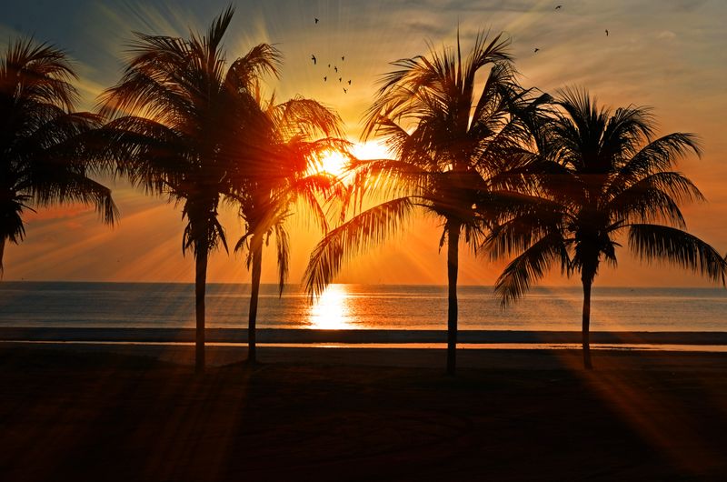 Malaysian beach sunset with golden orange sky over calm tropical ocean