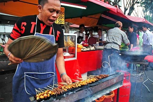 Malaysian satay grilled chicken skewers on charcoal grill with peanut sauce